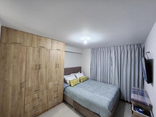 クスコにあるApartamento Con Terrazaのベッドルーム1室(ベッド1台付)、大きな木製キャビネットが備わります。
