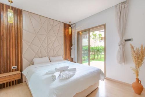 um quarto com uma cama branca com um laço em Résidence Golfique PJ, jardin, piscine em Marrakech
