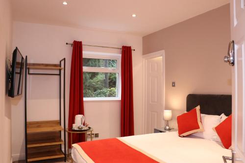 a bedroom with a bed with red curtains and a window at Dalesgate Hotel - Self Check In in Keighley