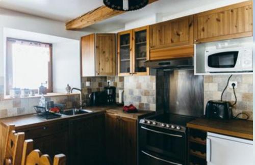 eine Küche mit Holzschränken und einem Herd mit Backofen in der Unterkunft Au cœur du massif jurassien in Les Rousses