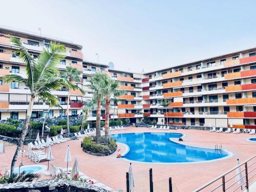 a large apartment complex with a swimming pool and palm trees at Casa Lea Los Gigantes in Puerto de Santiago