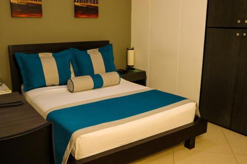 a bedroom with a large bed with blue and white pillows at hotel medellin gold in Medellín