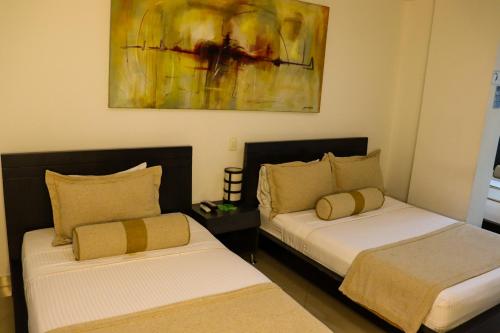 two beds in a room with a painting on the wall at hotel medellin gold in Medellín