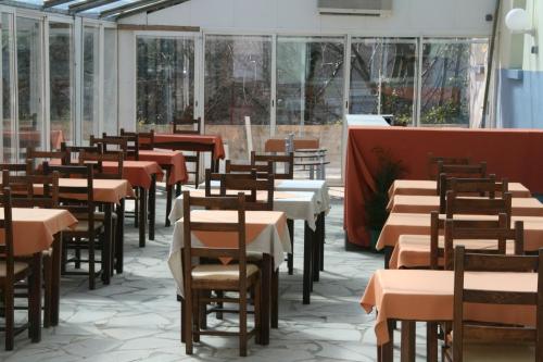 - une rangée de tables et de chaises dans une chambre avec fenêtres dans l'établissement Hotel Le Bois Des Espeisses, à Nîmes