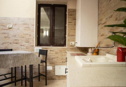 uma cozinha com um lavatório e uma mesa com cadeiras em Casa Colombo - The Fab Stay em Brindisi