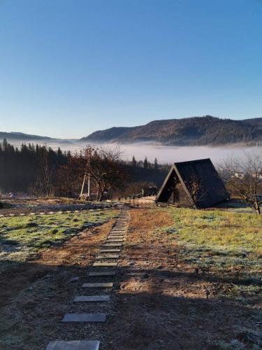 a path in a field with a barn and fog at Mirador Cottage in Slavske