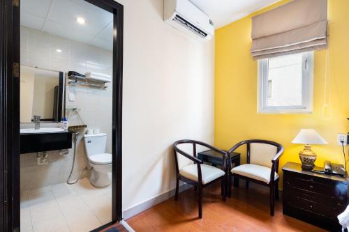 a bathroom with a toilet and a table and chairs at Sai Gon Hotel Bui Vien Walking Street in Ho Chi Minh City