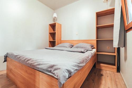 Schlafzimmer mit einem Bett mit einem Kopfteil aus Holz und Regalen in der Unterkunft Terme Banovci - Mobilne hiške Med Brajdami in Banovci