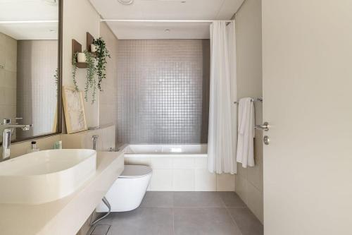 een badkamer met een wit bad, een wastafel en een bad tubermott bij Frank Porter - 1 Residences Al Wasl in Dubai