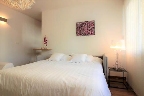 une chambre avec un lit blanc et une lampe dans l'établissement Vie en Rose Parking 2 min du Lac, à Annecy