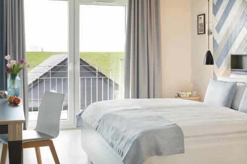 1 dormitorio con cama, escritorio y ventana en Ferienwohnungen Küstenperle, en Büsum