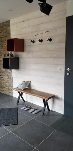 - un banc en bois dans une pièce avec des chaussures au sol dans l'établissement La terrasse des volcans, à Saint-Genès-Champanelle