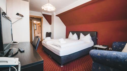 a hotel room with a bed and a tv and a couch at Hotel Kärntnerhof Velden by S4Y in Velden am Wörthersee