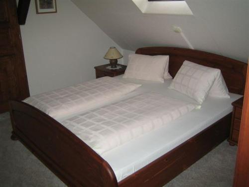 a bed with a wooden frame and white sheets and pillows at Pension Anna in Český Krumlov