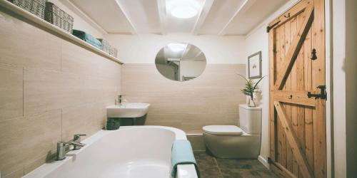 La salle de bains est pourvue d'une baignoire, de toilettes et d'un miroir. dans l'établissement Church Cottage - Quaint farmhouse cottage with modern twist, Dog Friendly, Sleeps 6-7, à West Down