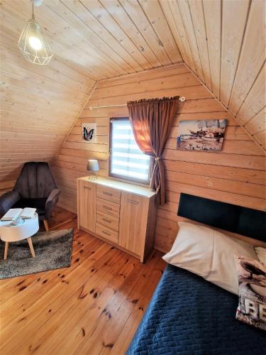 a bedroom with a bed and a chair in a room at Domki U Ali w Rewalu in Rewal