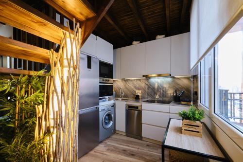 une cuisine avec des armoires blanches et une laveuse et une sécheuse dans l'établissement El Amarre - Apartamento boutique camarote frente a la playa - Grupo Querbes, à Gijón