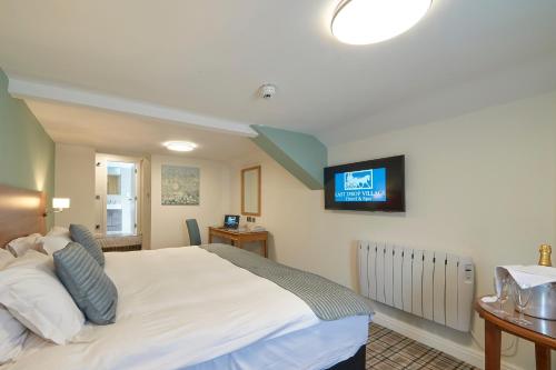 a bedroom with a white bed with a tv on the wall at Last Drop Village Hotel & Spa in Bolton