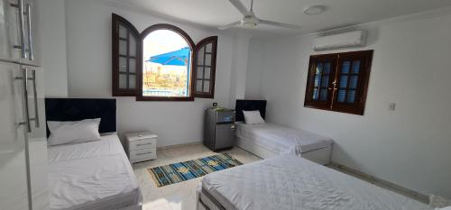 a bedroom with two beds and two windows at La Terrace in Aswan