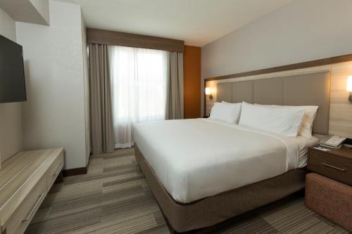 Un dormitorio con una gran cama blanca y una ventana en Holiday Inn Express & Suites S Lake Buena Vista, an IHG Hotel, en Kissimmee