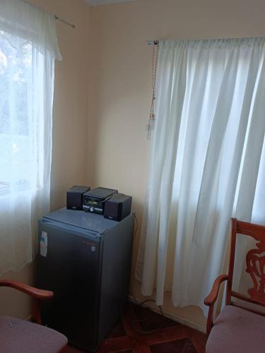 a room with a television and a window with curtains at Huerto El Tránsito in El Portillo