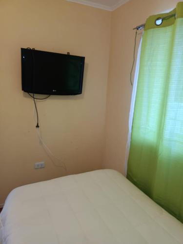 a bedroom with a bed and a television on the wall at Huerto El Tránsito in El Portillo