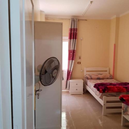 - une chambre avec un lit et un ventilateur à côté d'une porte dans l'établissement Sweet Home- No Egyptian, à Hurghada