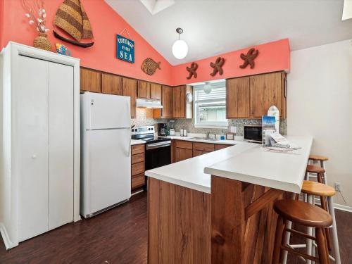 Una cocina con refrigerador blanco y gabinetes de madera. en Bermuda Bungalow, en Galveston