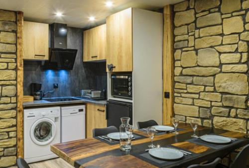 - une cuisine avec une table et un mur en pierre dans l'établissement Appartement Le Cuchon St-Léger-les-Mélèzes, à Saint-Léger-les-Mélèzes