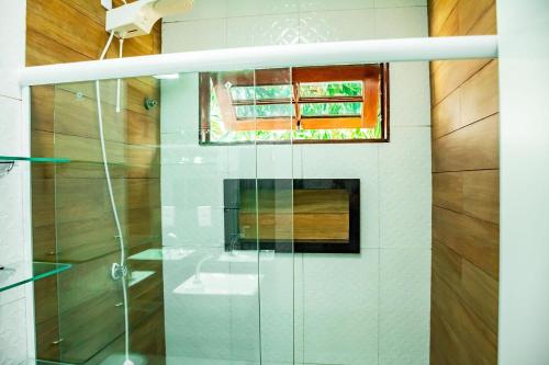 a glass shower in a bathroom with a window at Casa em cond fechado em Barra de Santo Antonio AL in Barra de Santo Antônio