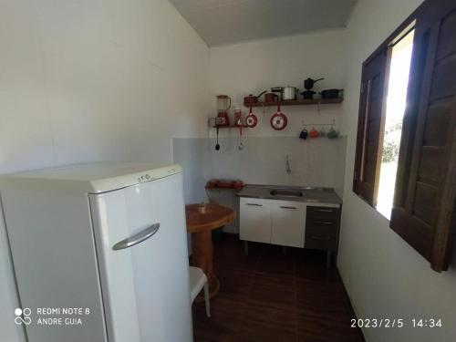 a small kitchen with a refrigerator and a table at Encontro dos passaros in Ibicoara