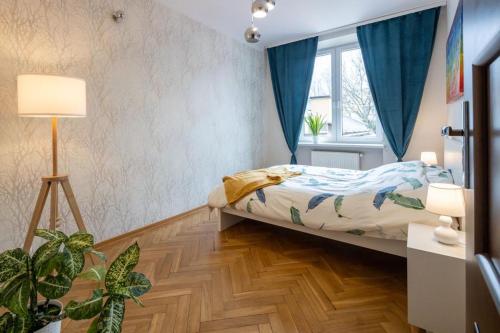 um quarto com uma cama com cortinas azuis e piso em madeira em Justi Old Town Apartment Studencka em Cracóvia