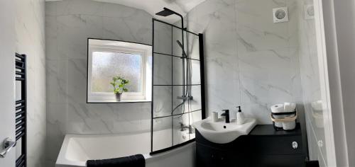 a bathroom with a tub and a sink and a mirror at Gateway Getaway in Horsforth Sleeps 7 in Leeds