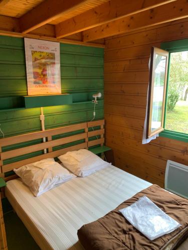 1 dormitorio con 1 cama en una cabaña de madera en Camping municipal de la Lande, en Nexon
