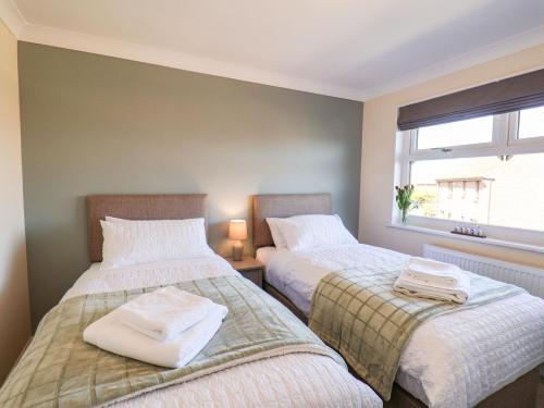 two beds in a room with a window at Prestella in Filey