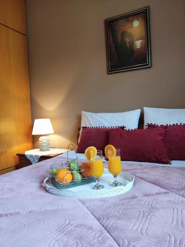 a tray of fruit on a bed with two glasses of orange juice at Room Ntina Kastraki in Kastraki