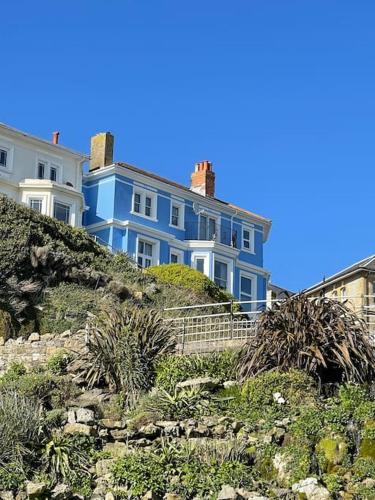a blue house sitting on top of a hill at Top Deck - Fresh, stylish seaside apartment in Ventnor