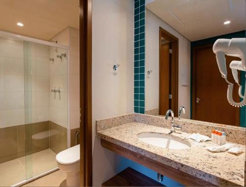 a bathroom with a sink and a shower and a toilet at Apartamento Resort Solar das Águas em Olímpia in Olímpia