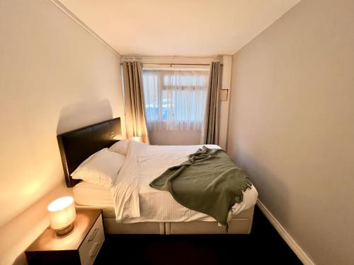 a small bedroom with a bed and a window at Beach Court Ground Floor - Cosy Apartment with Sea Views in Saundersfoot