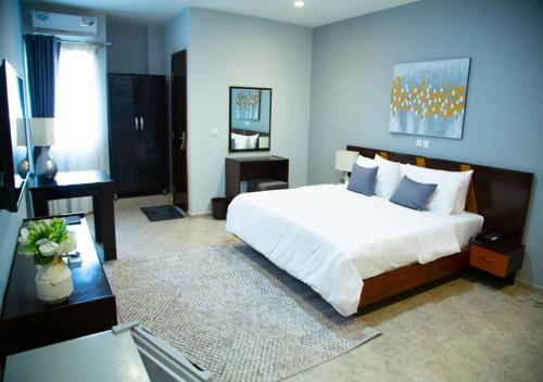 a bedroom with a large white bed and a desk at ONYX HOTEL Yamoussoukro in Yamoussoukro