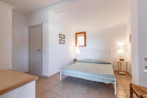 a white bedroom with a bed and a bathroom at Agriturismo Casa Marmida in Pardu Atzei