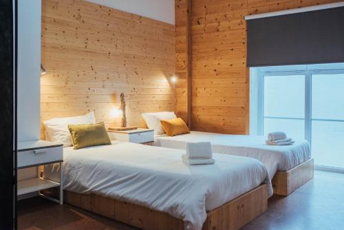 2 łóżka w pokoju z drewnianymi ścianami w obiekcie Shark's Lodge w mieście Baleal