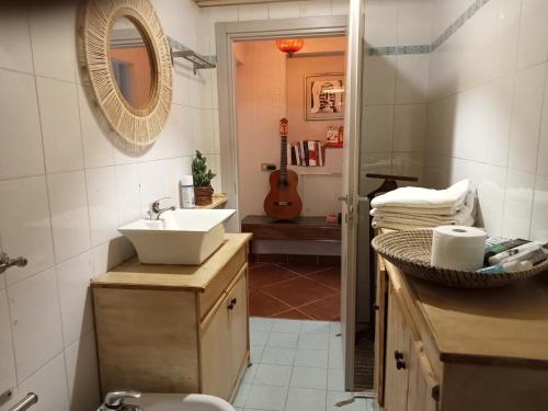 een badkamer met een wastafel, een spiegel en een gitaar bij Mango House in Milano Marittima