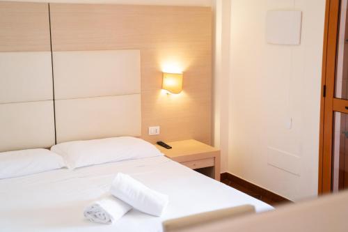 a bedroom with two beds and a light on a wall at Taormina Hotel Calipso in Mazzeo