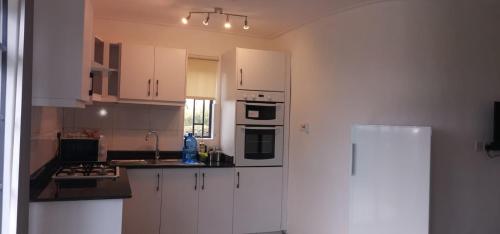 a kitchen with white cabinets and a refrigerator at Elwai Centre cottages- Newly constructed perfect for families in Heni Village