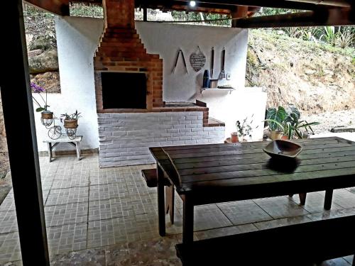 un patio con chimenea y mesa de madera en Sítio Completo, na estrada de Aldeia Velha, com rio a frente da porteira, en Silva Jardim