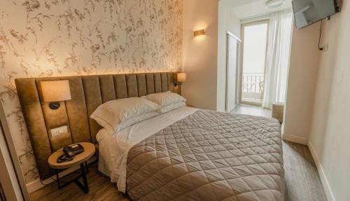 a bedroom with a bed and a table with a lamp at Hotel Du Lac Gardone Riviera in Gardone Riviera