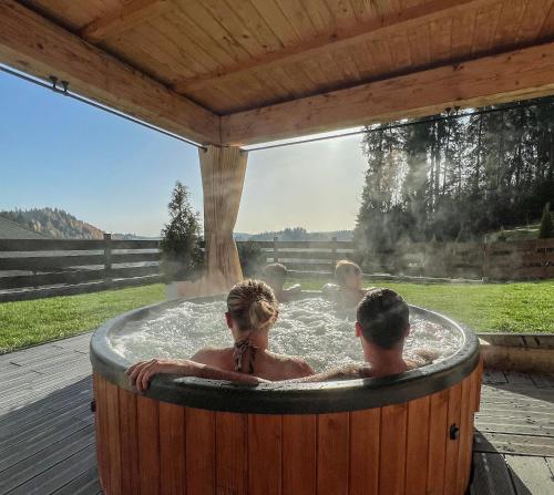 a man and woman in a hot tub on a deck at Dom na Zielonym Wzgórzu z własną Sauną i Jacuzzi in Łapsze Niżne