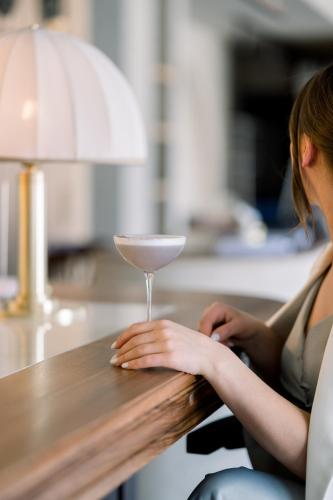 a woman sitting at a counter with a cocktail glass at Forest 1961 Boutique Hotel & Restaurant in Vanadzor