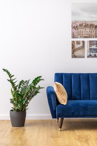 a blue couch in a living room with a plant at Apartment Dąbrowskiego by The Railway Station Wroclaw in Wrocław
